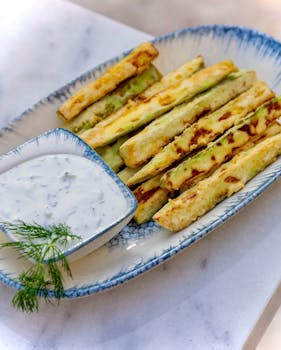 A curious cat sniffing a bowl of tzatziki placed on a kitchen countertop.